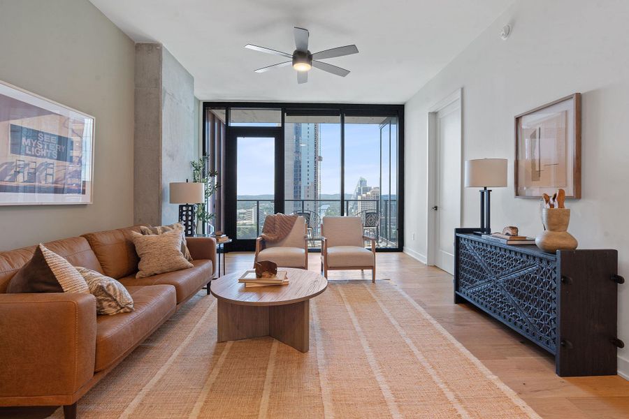 Representative Photo. Open Concept living room with 7.5" wide Bella Cera hardwood flooring, recessed lighting, ceiling fan, and a balcony off the living room with a West view