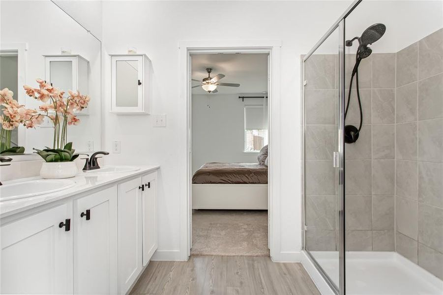 Modern bathroom featuring a dual vanity with white cabinetry, black hardware, and an expansive mirror
