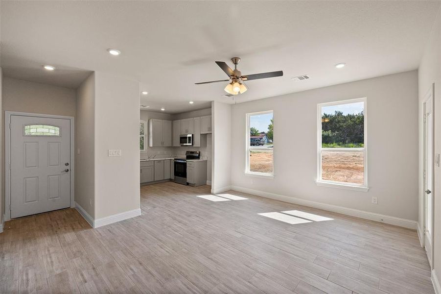 Kitchen with sink, light stone countertops, light hardwood / wood-style flooring, and stainless steel appliances