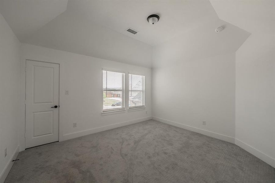 This room features light gray carpeting, white walls, and a vaulted ceiling