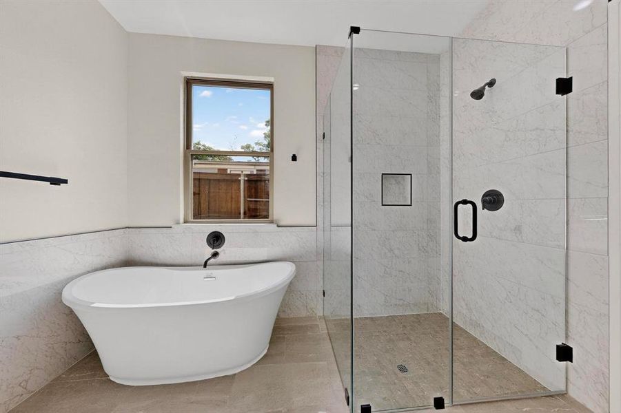 Full bath with tile walls, a freestanding bath, a stall shower, wainscoting, and tile patterned floors Full bath with tile walls, a freestanding bath, a stall shower, wainscoting, and tile patterned floors