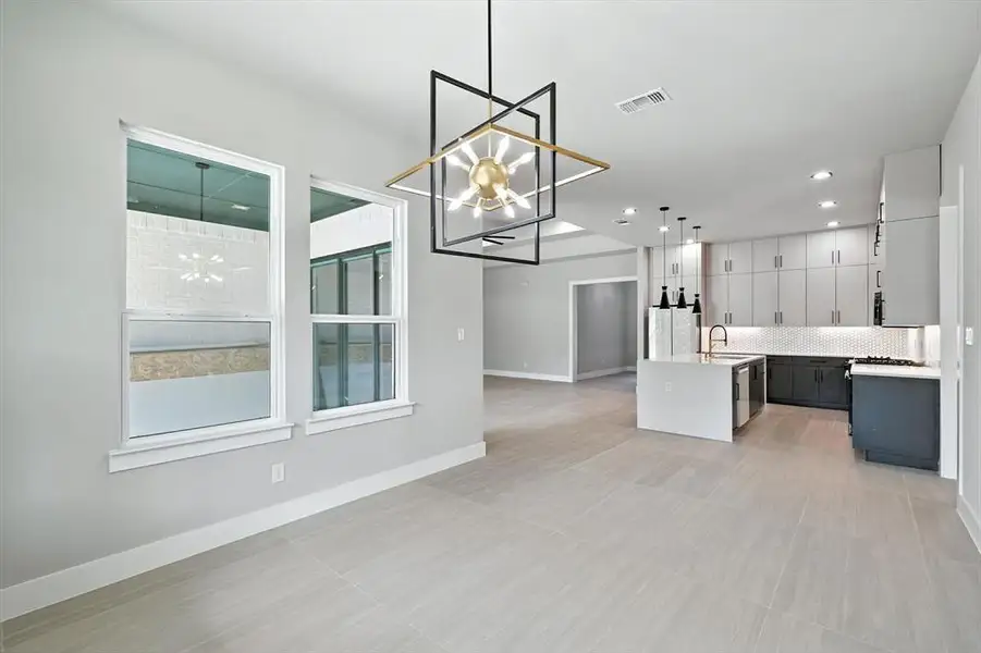 Kitchen featuring a chandelier, a kitchen island with sink, white cabinetry, backsplash, and open floor plan Kitchen featuring a chandelier, a kitchen island with sink, white cabinetry, backsplash, and open floor plan