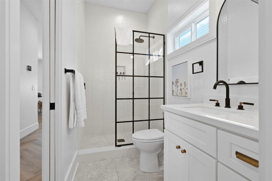 The third bedroom enjoys a private bath designed with sophistication in mind—featuring a sleek open shower with bold black fixtures, a toilet, and a built-in vanity with under-sink storage. The third bedroom enjoys a private bath designed with sophistication in mind—featuring a sleek open shower with bold black fixtures, a toilet, and a built-in vanity with under-sink storage.