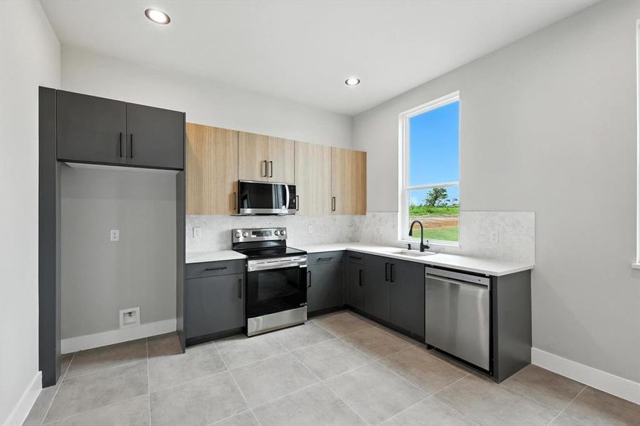 Kitchen with stainless steel appliances, decorative backsplash, light countertops, recessed lighting, and light tile patterned floors