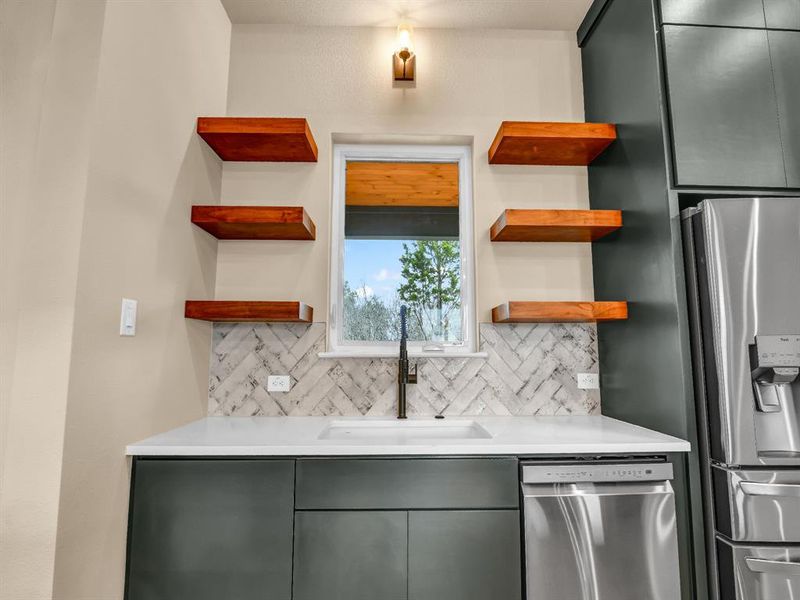 Kitchen with gray cabinetry, decorative backsplash, sink, and stainless steel appliances