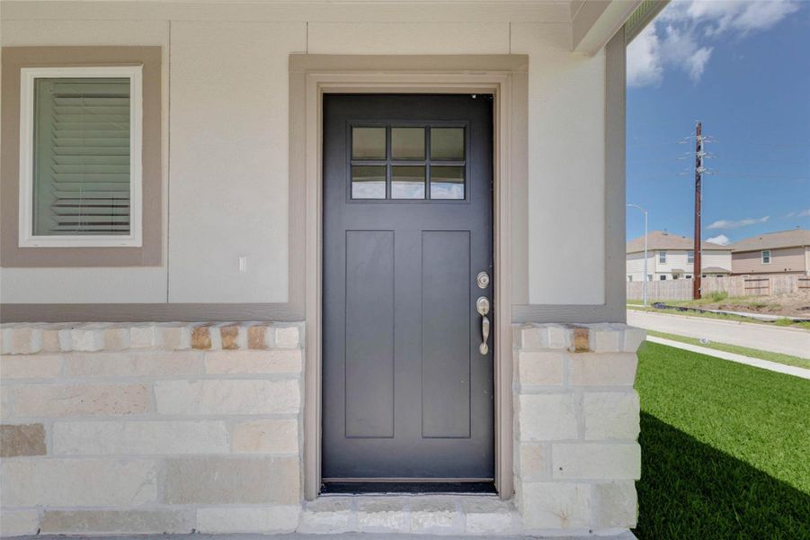 The covered front entry offers a closer look at the home’s stylish black door, stone accents, and clean trim details. A nearby window brings balance to the facade, while the porch area provides a welcoming transition into the home with a simple, modern, and polished exterior design. The covered front entry offers a closer look at the home’s stylish black door, stone accents, and clean trim details. A nearby window brings balance to the facade, while the porch area provides a welcoming transition into the home with a simple, modern, and polished exterior design.
