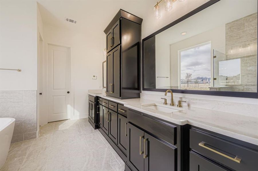 Full bathroom with double vanity, a soaking tub, and a tile shower
