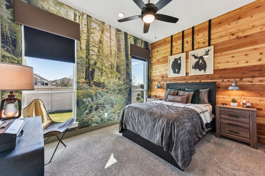 Natural wood paneling pairs with tall windows in this comfortable secondary bedroom.