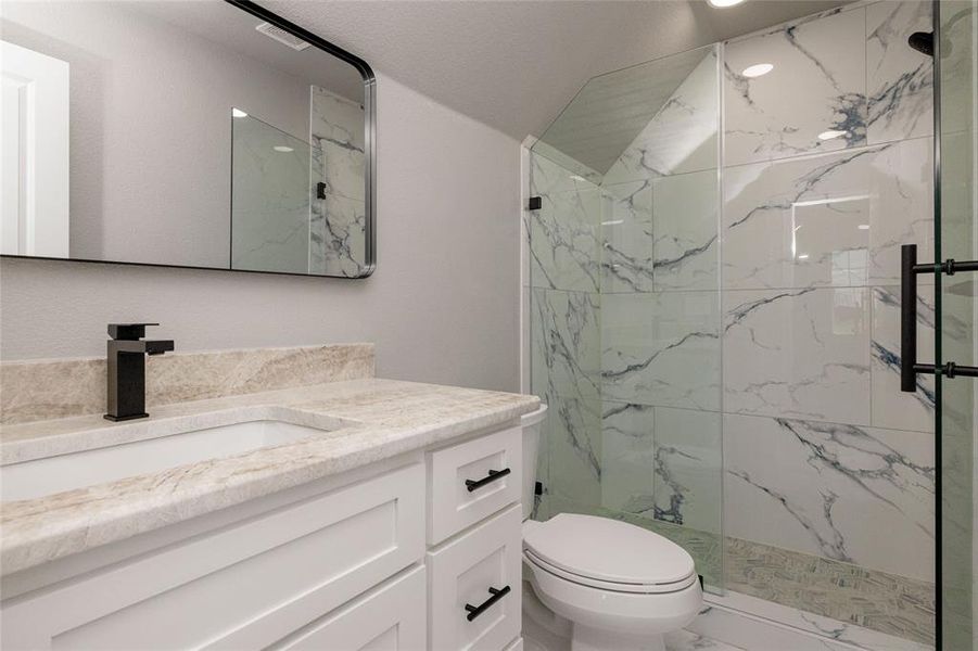 Bathroom featuring toilet, marble finish floor, vanity, and a marble finish shower Bathroom featuring toilet, marble finish floor, vanity, and a marble finish shower