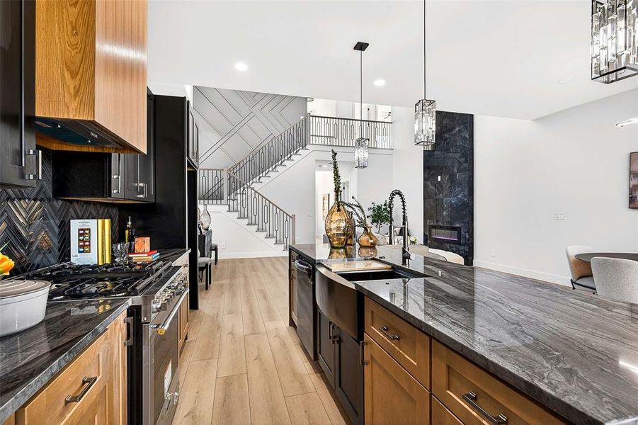 Kitchen with dark stone counters, pendant lighting, stainless steel range with gas stovetop, brown cabinets, and recessed lighting Kitchen with dark stone counters, pendant lighting, stainless steel range with gas stovetop, brown cabinets, and recessed lighting