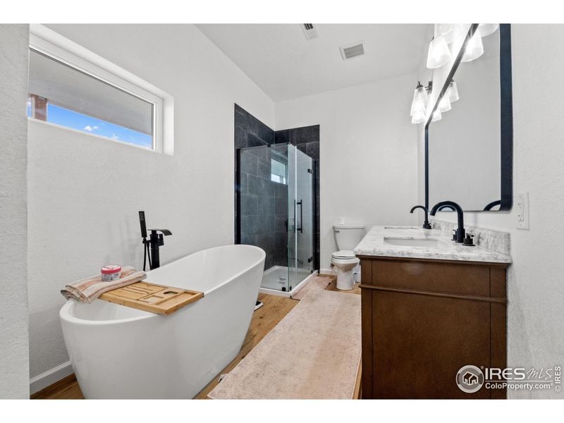 Luxurious 5-piece master bath featuring a freestanding soaking tub, walk-in tiled shower, dual-sink vanity with marble countertop, and modern fixtures-creating a true spa-like retreat at home.