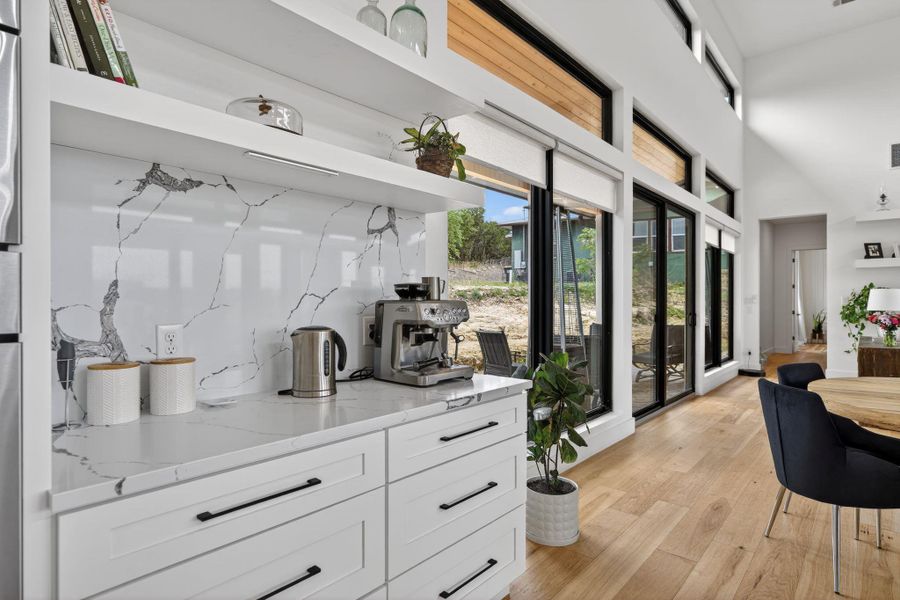 Bar featuring white cabinets, Quartz countertops, light wood-type flooring, a high ceiling, and open shelves