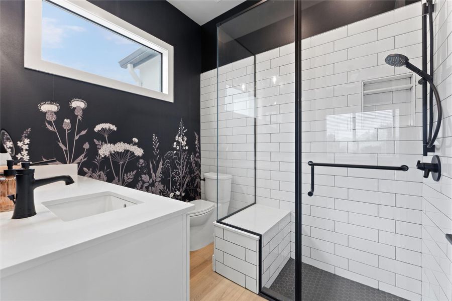 Spacious bathroom featuring a frameless glass shower enclosure with white subway tile and a built-in bench Spacious bathroom featuring a frameless glass shower enclosure with white subway tile and a built-in bench