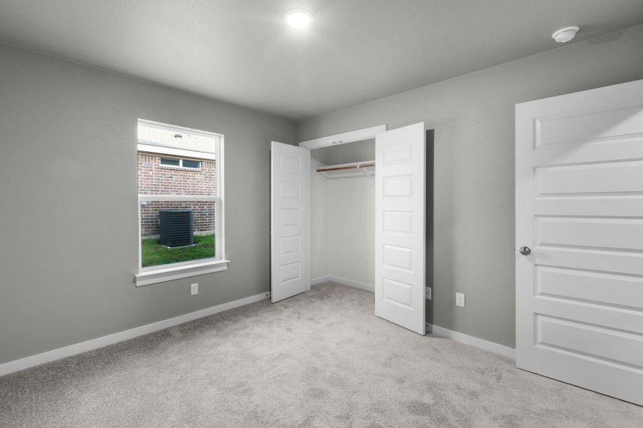 A well-lit bedroom features plush carpeting and a convenient walk-in closet.