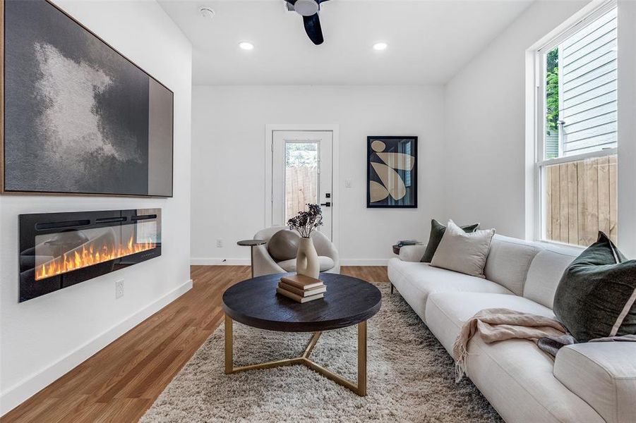 Living area with plenty of natural light, wood finished floors, a glass covered fireplace, recessed lighting, and a ceiling fan Living area with plenty of natural light, wood finished floors, a glass covered fireplace, recessed lighting, and a ceiling fan