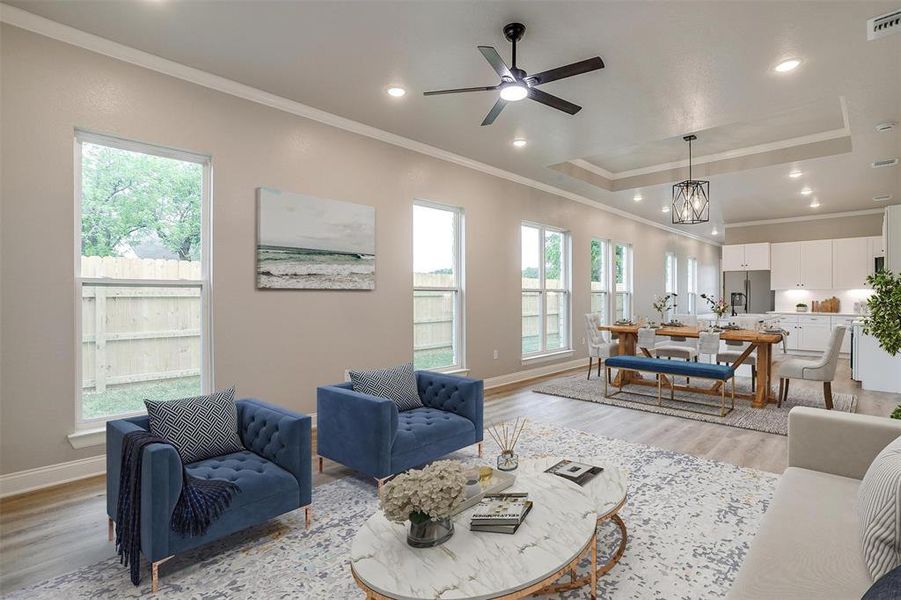Living room featuring plenty of natural light, ornamental molding, a tray ceiling, and light wood-type flooring Living room featuring plenty of natural light, ornamental molding, a tray ceiling, and light wood-type flooring