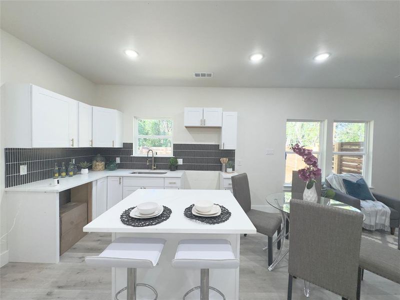 Kitchen featuring white cabinets, a center island, light hardwood / wood-style floors, and sink