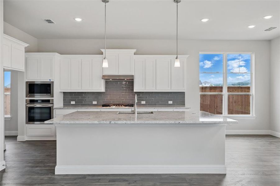 Kitchen featuring appliances with stainless steel finishes, a sink, baseboards, tasteful backsplash, and white cabinets Kitchen featuring appliances with stainless steel finishes, a sink, baseboards, tasteful backsplash, and white cabinets