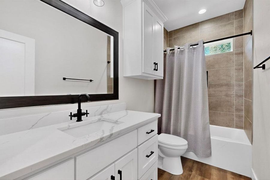 Full bathroom with dark wood-style flooring, shower / tub combo with curtain, vanity, and recessed lighting