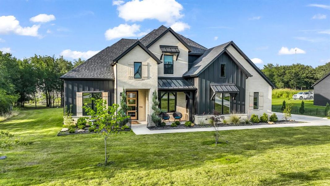 Back of property featuring board and batten siding, a shingled roof, a yard, a standing seam roof, and metal roof Back of property featuring board and batten siding, a shingled roof, a yard, a standing seam roof, and metal roof