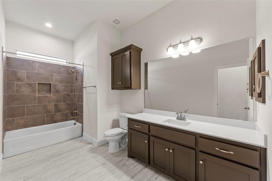 Full bathroom featuring tile patterned floors, tiled shower / bath, vanity, and toilet