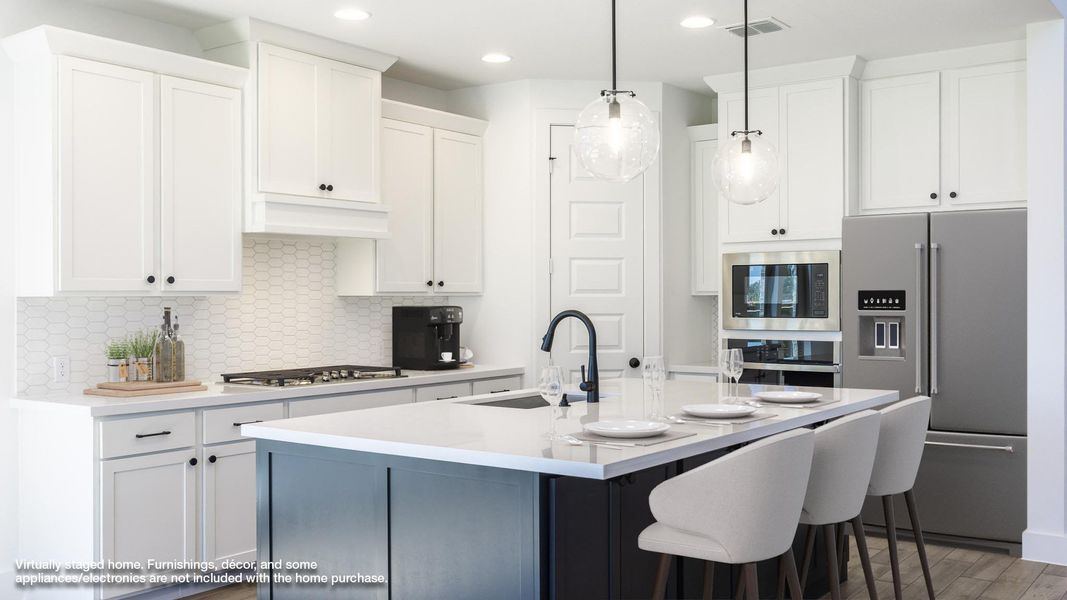 Kitchen featuring appliances with stainless steel finishes, backsplash, an island with sink, light stone countertops, and recessed lighting