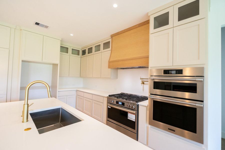 Built in microwave and oven. Custom white oak vent hood.36 inch professional style gas range