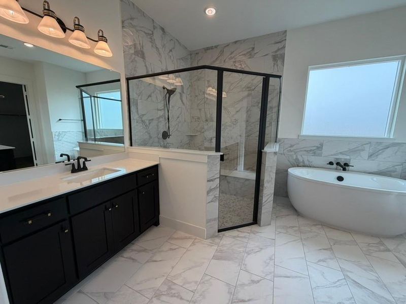 Bathroom with light marble finish floors, a soaking tub, vanity, a marble finish shower, and tile walls