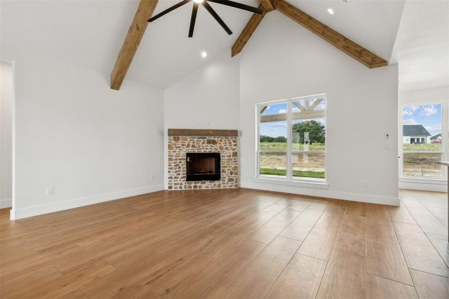 Unfurnished living room featuring a fireplace, a healthy amount of sunlight, beam ceiling, and light hardwood / wood-style floors