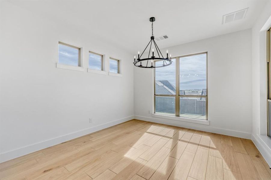 Unfurnished dining area with light wood-style flooring and hanging lights