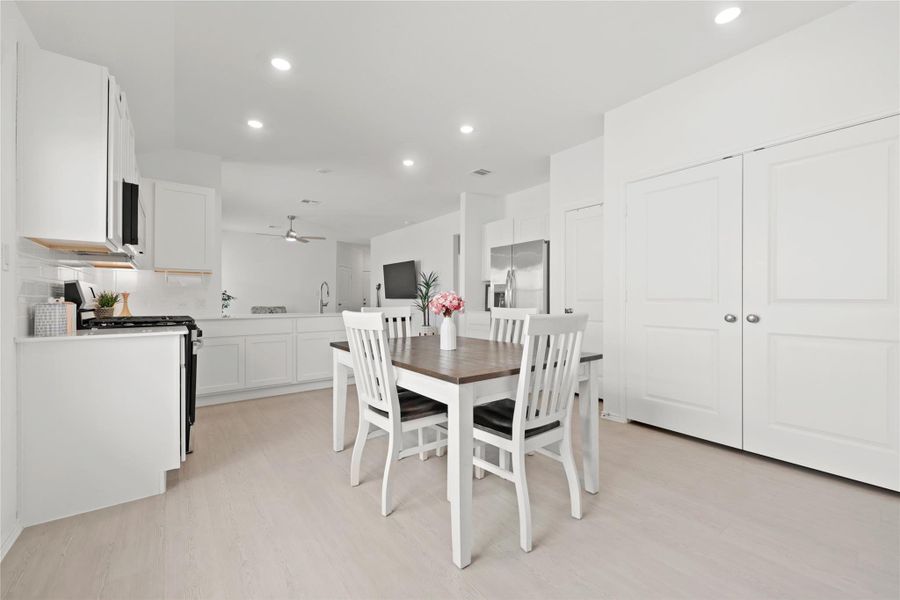 Generous pantry storage and white shaker cabinetry anchor this expansive dining area, which transitions effortlessly into the living room for a modern, open-concept feel.