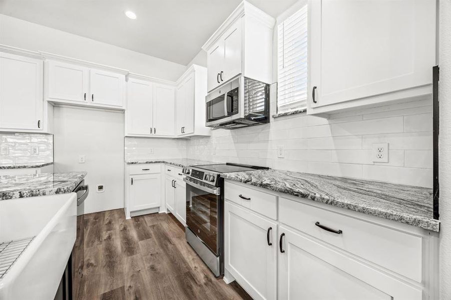 Kitchen featuring white cabinets, stainless steel appliances, tasteful backsplash, and dark hardwood / wood-style flooring