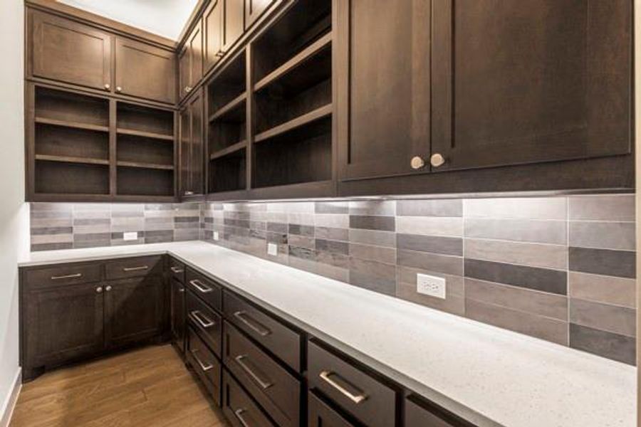 Kitchen with dark brown cabinets, tasteful backsplash, dark wood-type flooring, light stone counters, and open shelves Kitchen with dark brown cabinets, tasteful backsplash, dark wood-type flooring, light stone counters, and open shelves