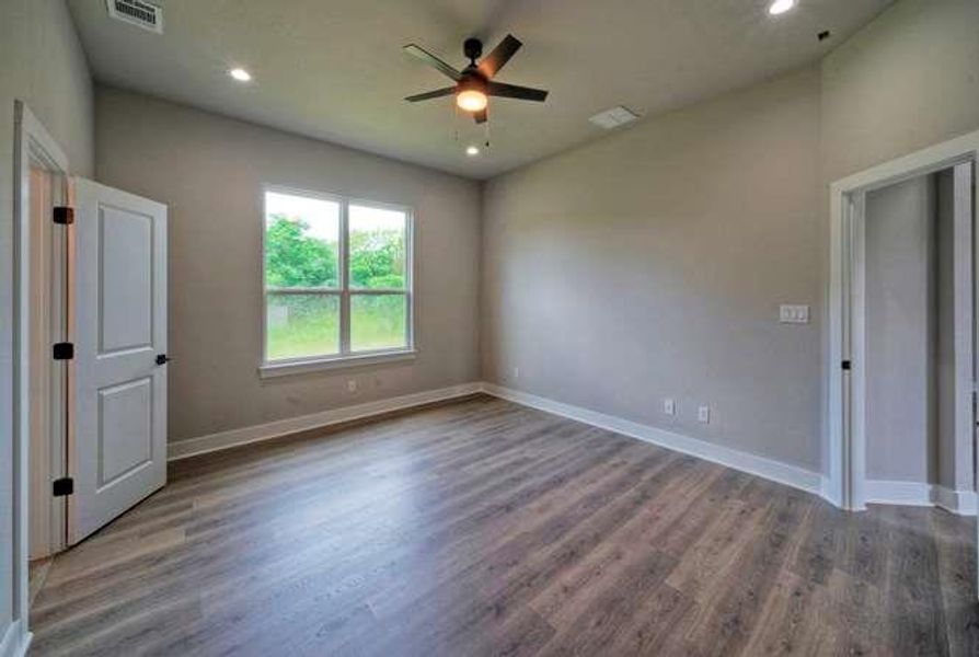 Laminate flooring and a ceiling fan create a comfortable atmosphere in this inviting space.