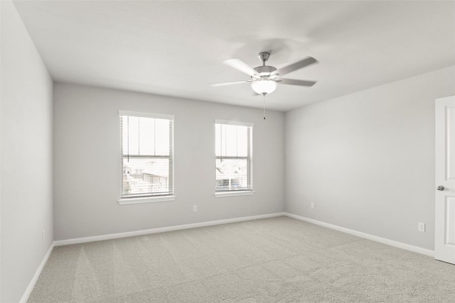Spare room featuring light colored carpet, a ceiling fan, and baseboards