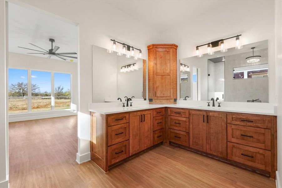 Bathroom with double vanity, plenty of natural light, and light wood-type flooring