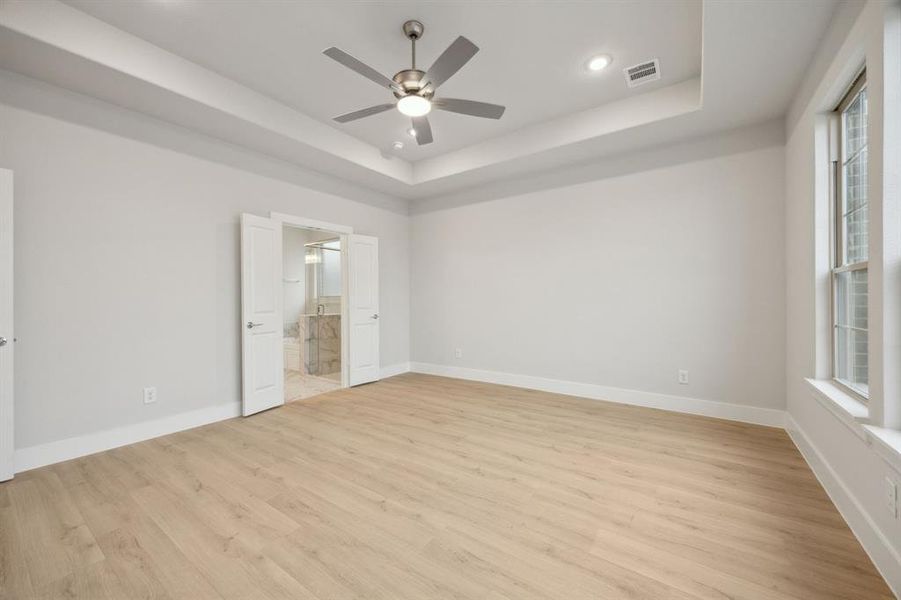 Spare room featuring ceiling fan, a raised ceiling, and light wood-type flooring