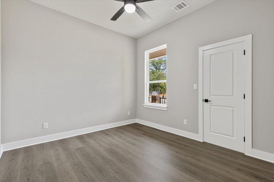 A well-lit room featuring durable flooring a ceiling fan.