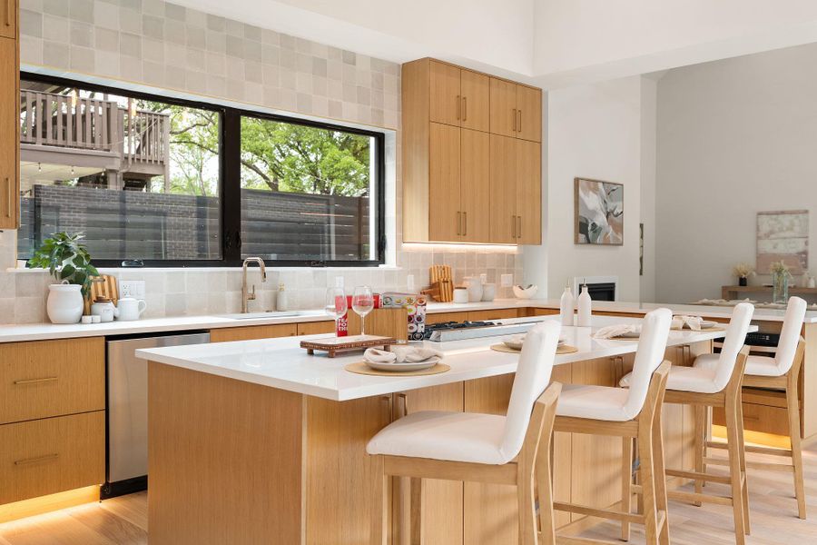 Kitchen featuring light wood-finish cabinetry, a large window over the sink, and a center island with countertop seating