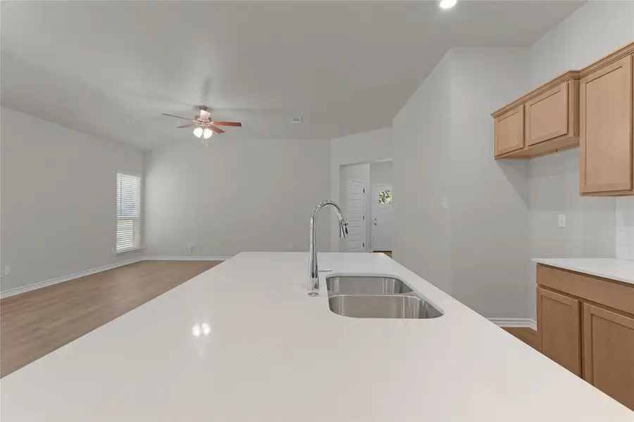 Kitchen with wood finished floors, light countertops, a ceiling fan, open floor plan, and lofted ceiling