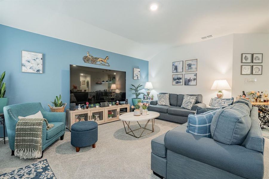 Carpeted living area with visible vents and vaulted ceiling