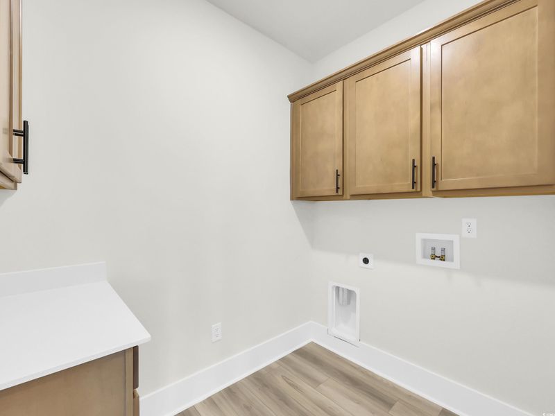 Laundry room with light wood-style flooring, washer hookup, electric dryer hookup, and cabinet space