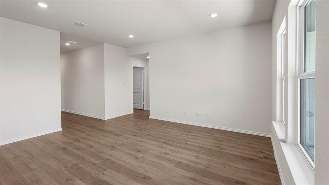 Spacious interior featuring wood-finish flooring, ample natural light from multiple windows, recessed ceiling lighting, and crisp white walls