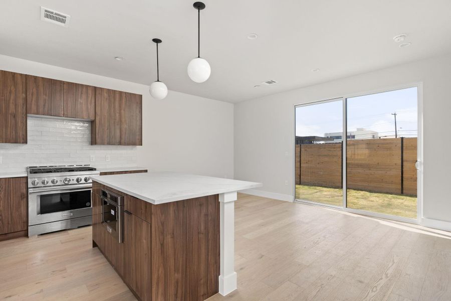 Kitchen with visible vents, backsplash, light wood-style flooring, modern cabinets, and high end stainless steel range