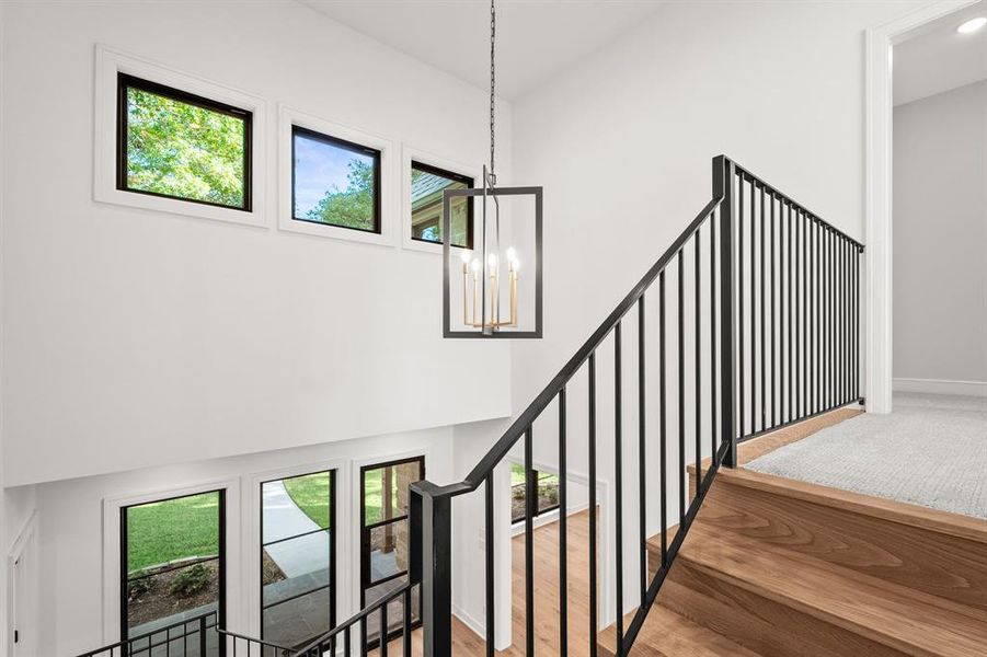 Stairs featuring a chandelier, a towering ceiling, and wood finished floors Stairs featuring a chandelier, a towering ceiling, and wood finished floors