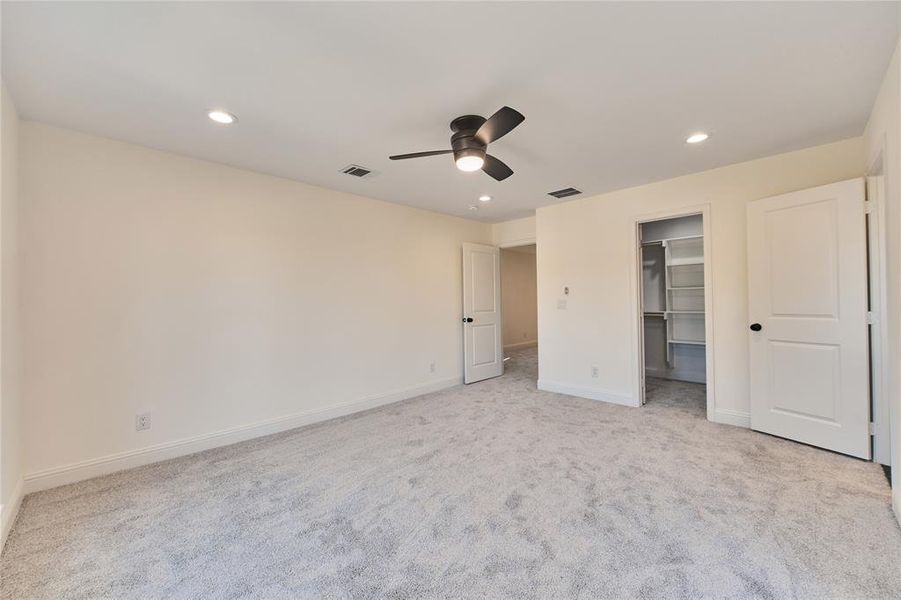 Unfurnished bedroom with a spacious closet, a closet, ceiling fan, and light carpet