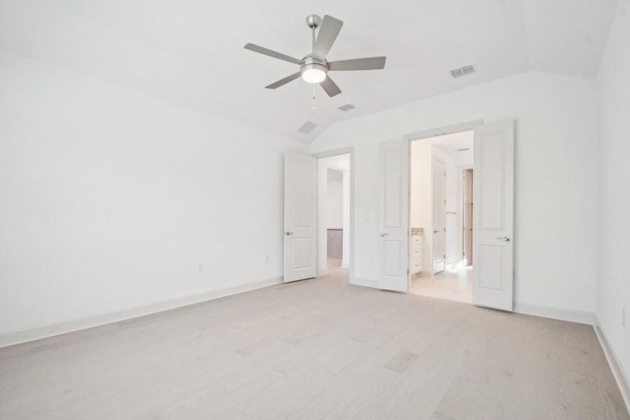 Unfurnished bedroom with vaulted ceiling, light wood finished floors, and ceiling fan Unfurnished bedroom with vaulted ceiling, light wood finished floors, and ceiling fan