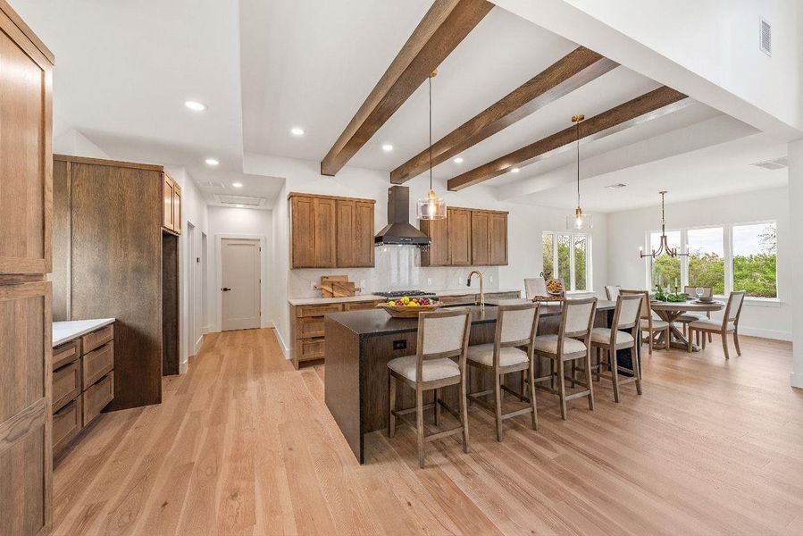 Expansive center island with a leathered waterfall granite countertop, abundant breakfast bar seating, and thoughtfully placed power outlets for added convenience.