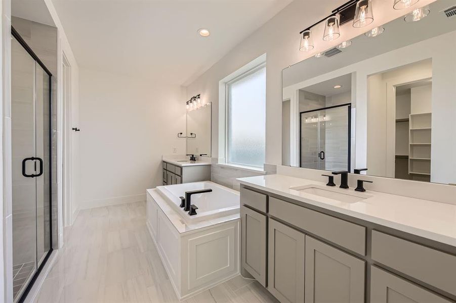 Bathroom featuring a shower stall, two vanities, a bath, recessed lighting, and baseboards Bathroom featuring a shower stall, two vanities, a bath, recessed lighting, and baseboards