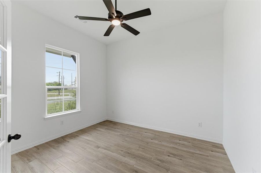 This room features a ceiling fan, a window, and light-colored flooring